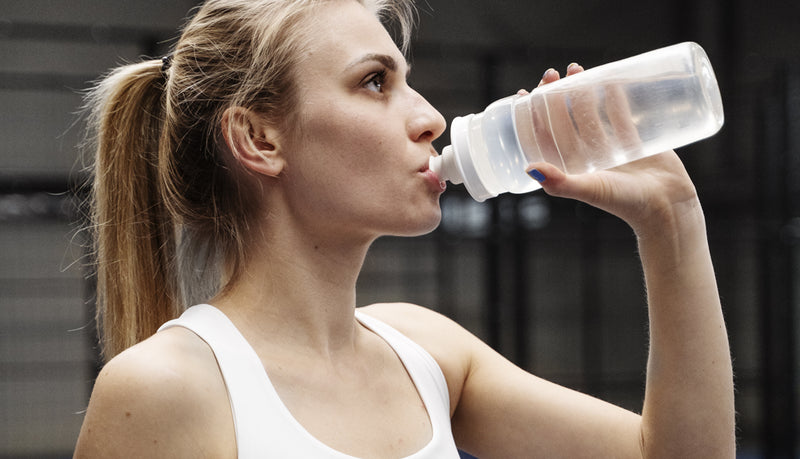 Athlete sipping Amino-XR intra-workout to reduce fatigue and support muscle recovery in a gym