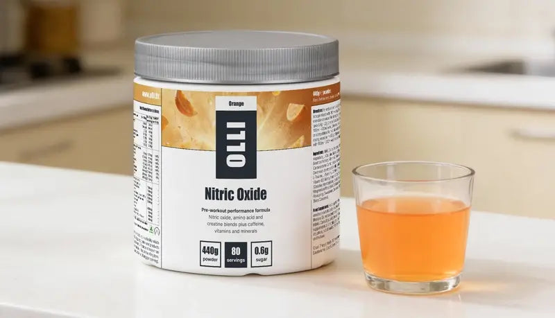 Container of OLLI Nitric Oxide supplement with a glass of orange liquid on a kitchen counter.
