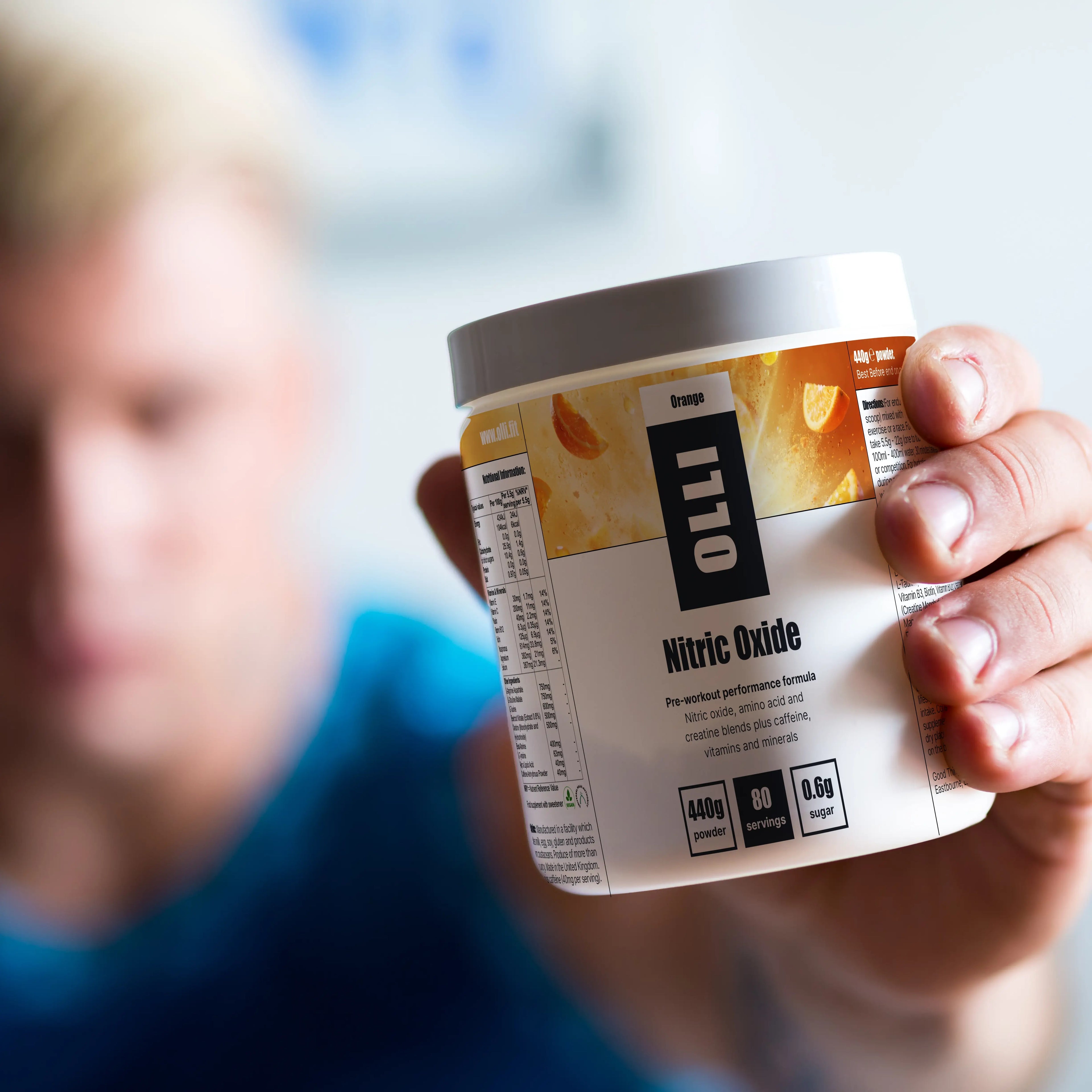 Person holding a container labeled 'Nitric Oxide' with a blurred background