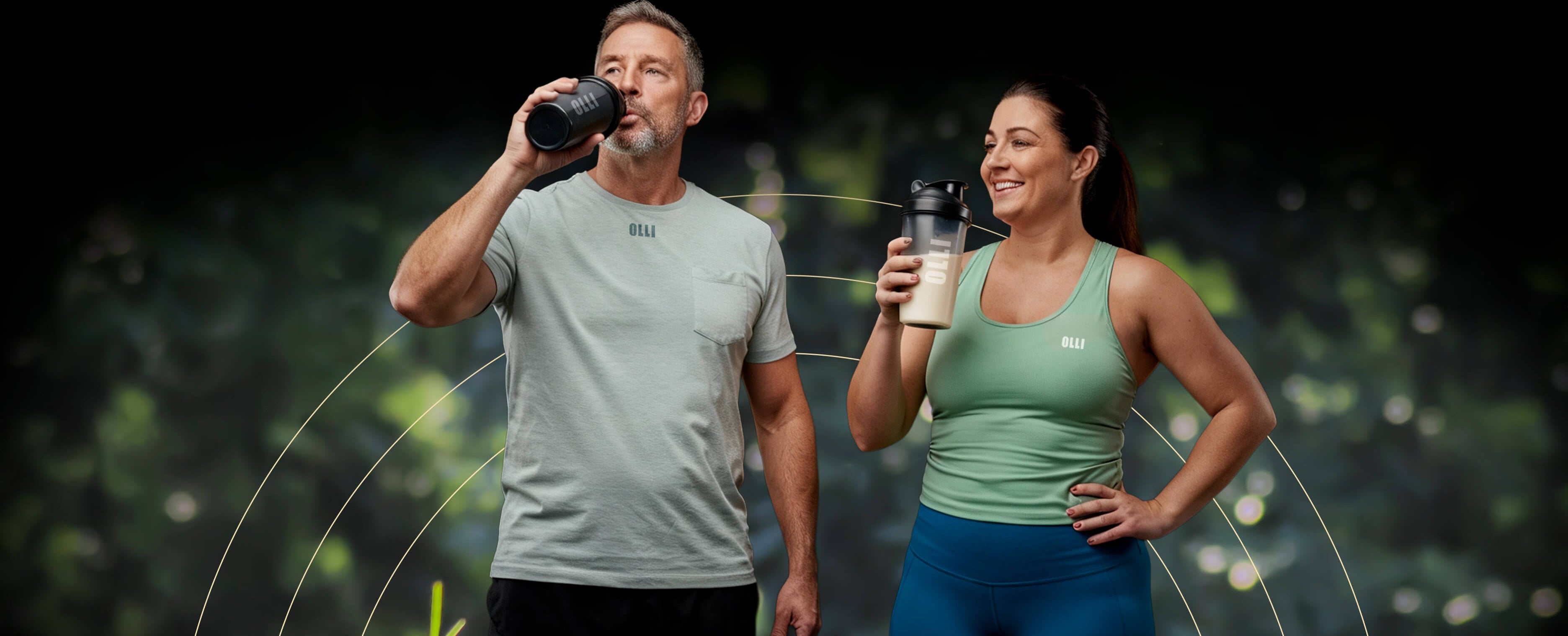 Man and woman holding protein shakers against a dark background