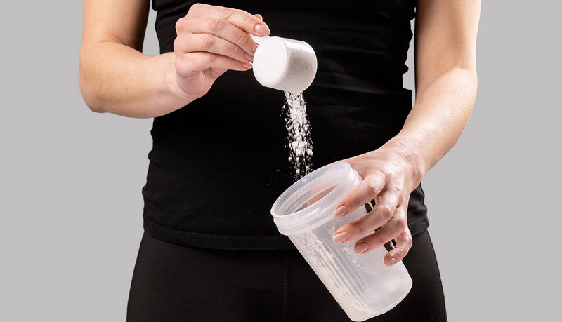 Woman pouring Olli creatine into shaker